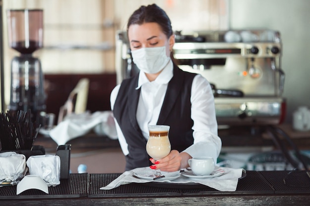 Kellnerin serviert Kaffee Latte in einem Glas