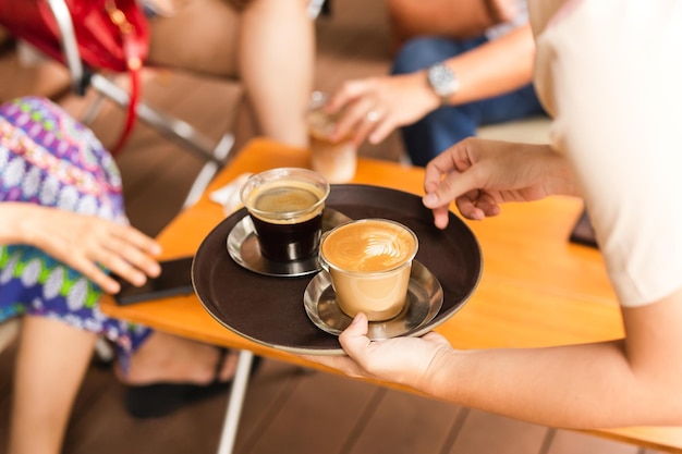 Kellnerin serviert Kunden einen heißen Kaffee im Café