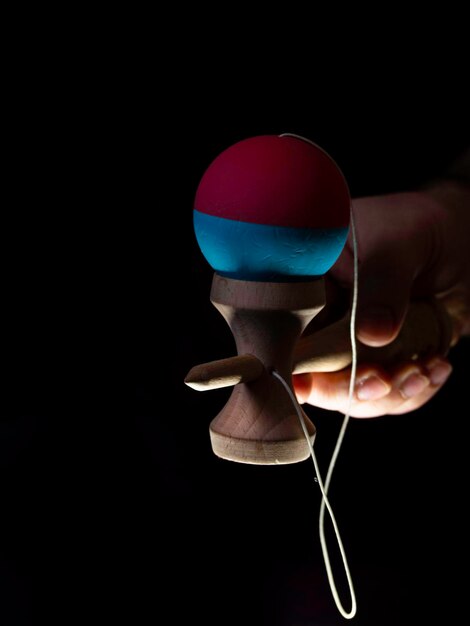 Kendama japanisches Spielzeug im schwarzen Hintergrund in der Hand