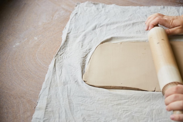 Foto keramikerin, die im töpferstudio arbeitet. die hände des keramikers schmutzig aus ton. prozess der herstellung von keramik. meisterkeramikerin arbeitet in ihrem atelier