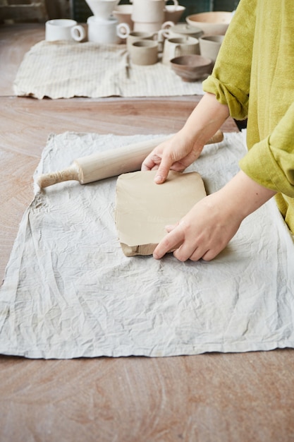 Keramikerin, die im Töpferstudio arbeitet. Die Hände des Keramikers schmutzig aus Ton. Prozess der Herstellung von Keramik. Meisterkeramikerin arbeitet in ihrem Atelier