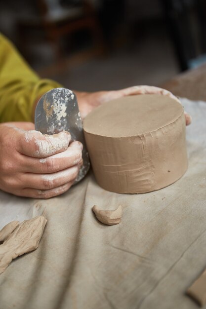 Keramikerin, die im Töpferstudio arbeitet. Die Hände des Keramikers schmutzig aus Ton. Prozess der Herstellung von Keramik. Meisterkeramikerin arbeitet in ihrem Atelier