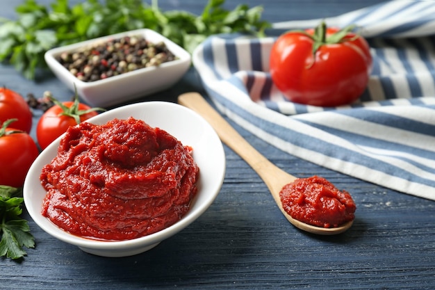 Keramikschale mit Tomatensauce und Zutaten auf Holztisch