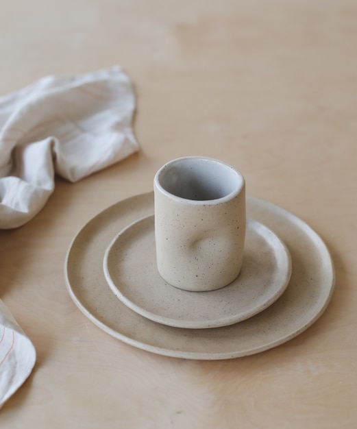 Keramiktasse und Teller auf einem Holztisch Draufsicht minimalistisches Set aus handgefertigtem Keramikgeschirr und ...