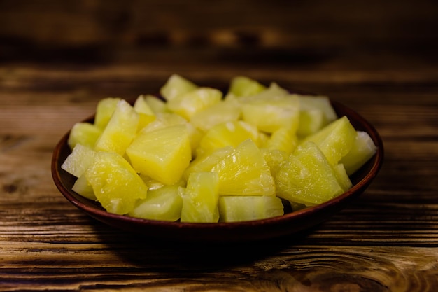 Keramikteller mit gehackter Ananas aus der Dose auf rustikalem Holztisch