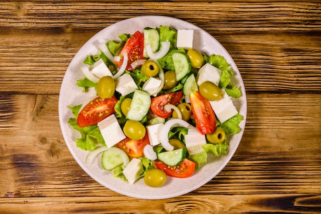 Keramische Platte mit griechischem Salat auf rustikalem Holztisch Draufsicht