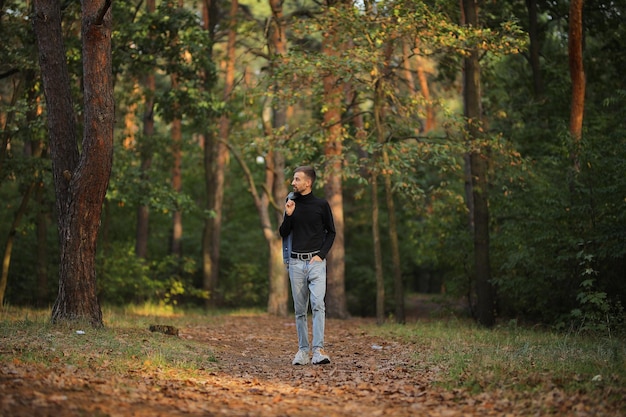 Kerl auf einem Spaziergang im Herbst Glücklicher Kerl Ein Mann geht im Park spazieren Der Kerl im schwarzen Golf