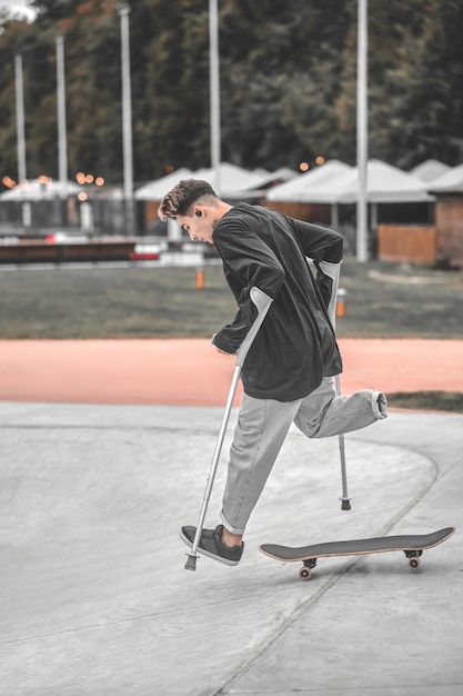 Kerl auf Krücken springt vom Skateboard