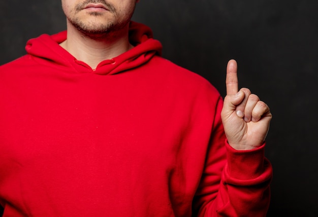 Kerl im roten Sweatshirt zeigen Fingerpunktgeste auf dunkler Wand