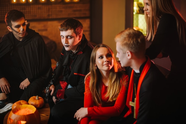 Foto kerl in graf draculas halloween-kostüm sitzt mit freunden in einem café