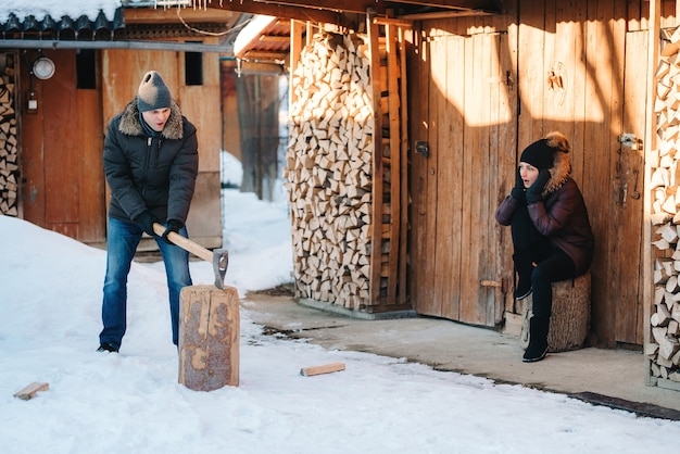 Kerl in Winterkleidung Holzhacken im Hof, mit Schnee bedeckt