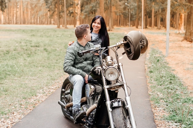 Kerl mit einem Mädchen im Park auf einem Motorrad