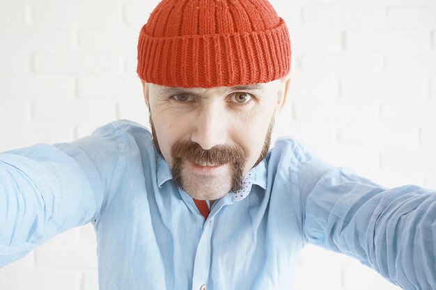 Foto kerl mit einem schnurrbart in einer roten strickmütze