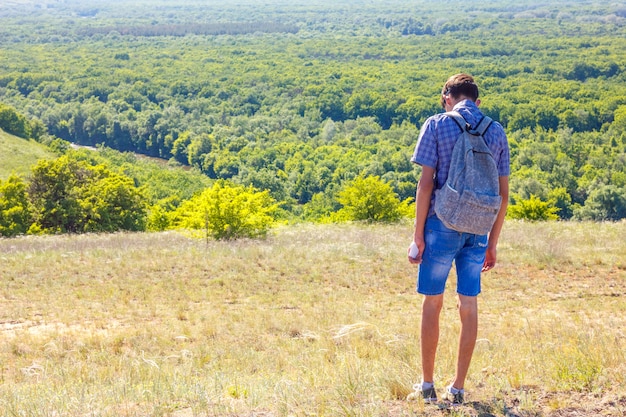 Kerl stehend auf einem Hügel mit Rucksack Reisekonzept getönt
