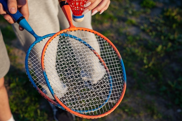 Kerl und Mädchen, die Badmintonschläger über Gras halten