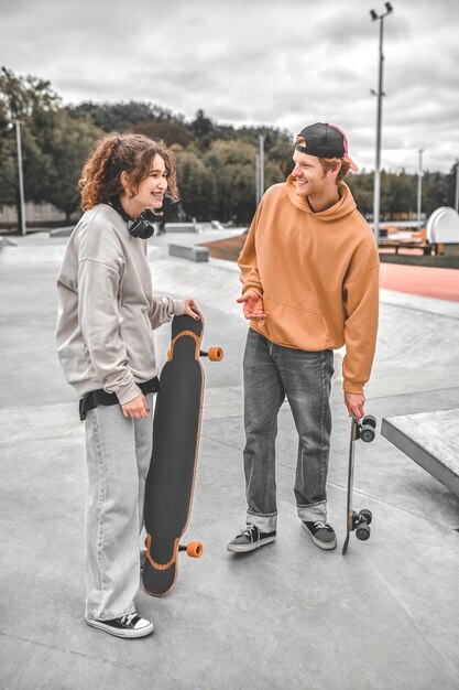 Kerl und Mädchen mit Skateboards haben Spaß an der Kommunikation