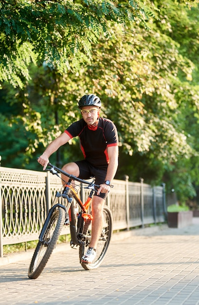 Kerlradfahrerreiten auf fahrrad nahe grünem park