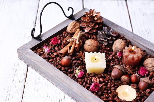 Kerzen auf Vintage-Tablett mit Kaffeebohnen und Gewürzen, Beulen auf farbigem Holzhintergrund wooden