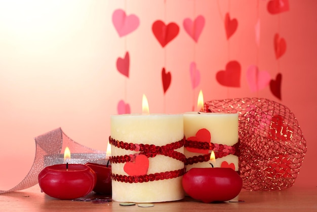 Kerzen zum Valentinstag auf Holztisch auf rotem Grund