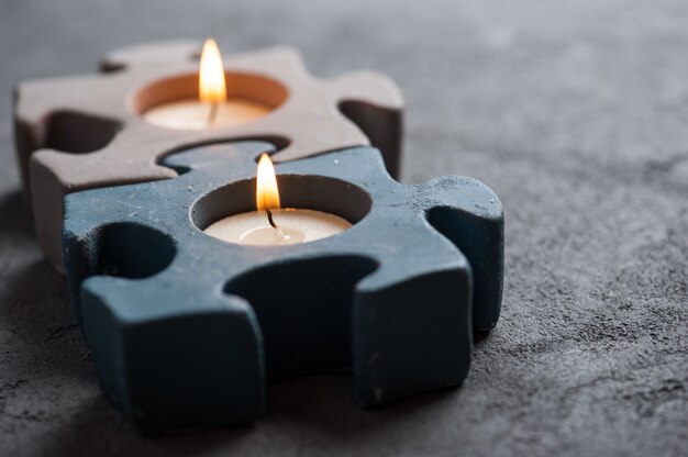 Kerzenhalter mit brennenden Kerzen auf Steinhintergrund