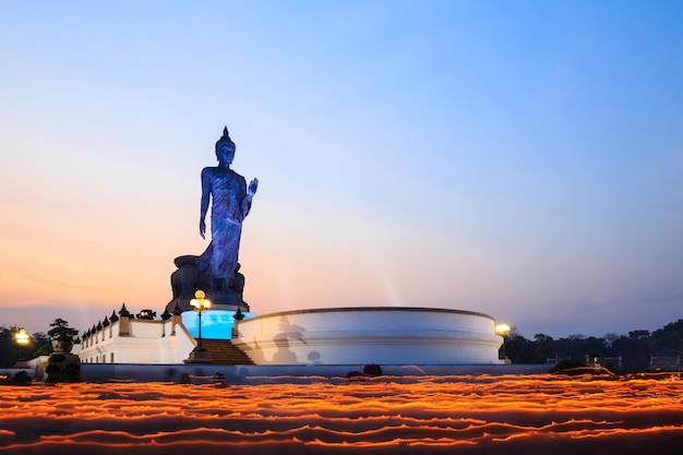 Kerzenlichtspur der Kerzenlichtzeremonie in der Dämmerung mit brennenden Kerzen in der Hand um die Buddha-Statue