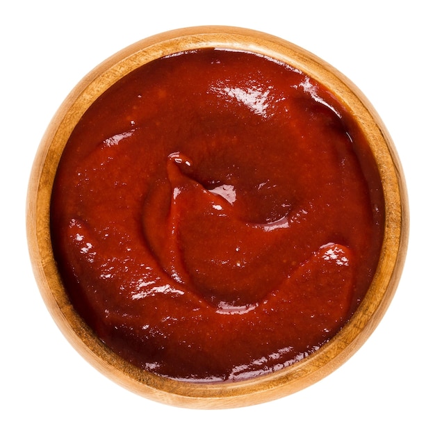Ketchup de tomate em uma tigela de madeira sobre branco