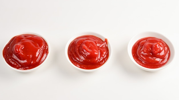 Ketchup en plato blanco sobre fondo blanco.
