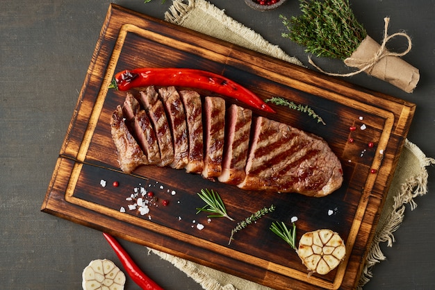 Keto dieta cetogênica bife, striploin frito grelhado na tábua na mesa marrom escura