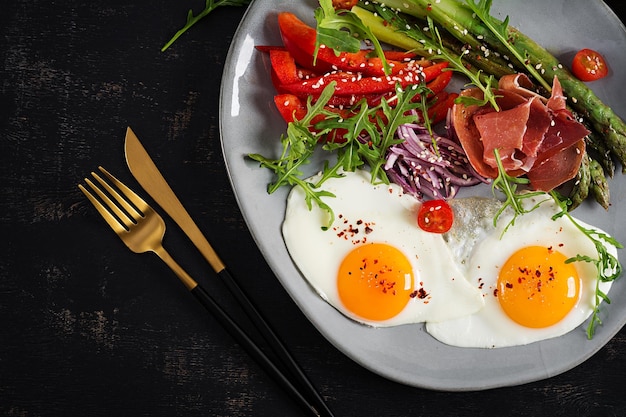 Keto-Frühstück Gebratener Spargel mit gebratenen Eiern und Prosciutto oder Jamon Ketogene Diät Gesundes Essen Draufsicht flach liegend