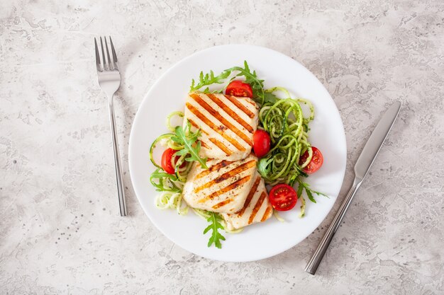 Foto ketogenes paläo-diät-mittagessen. halloumi-käse, spiralisierte zucchini mit rucola-pesto und tomaten