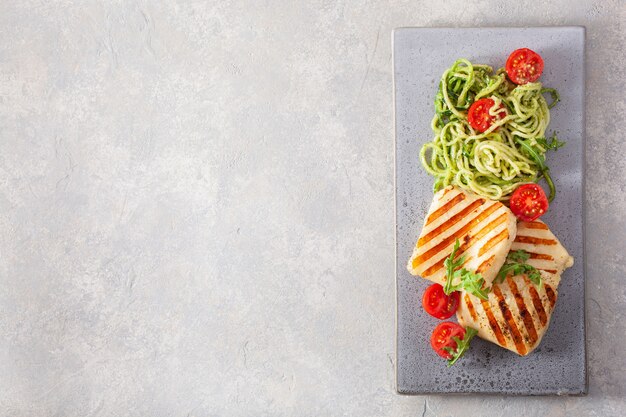 Ketogenes Paläo-Diät-Mittagessen. Halloumi-Käse, spiralisierte Zucchini mit Rucola-Pesto und Tomaten