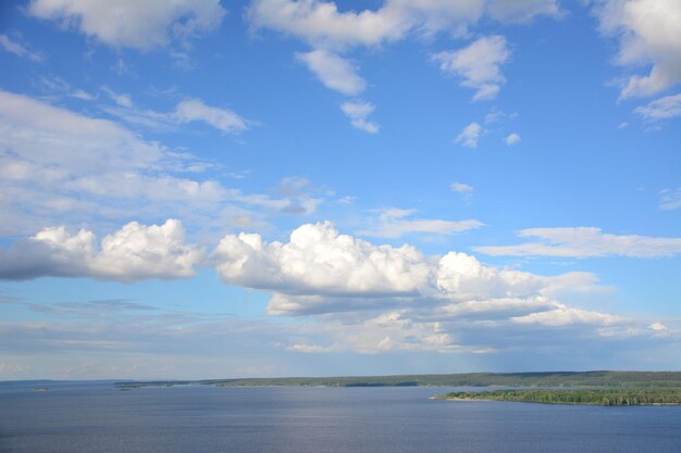 Kette weißer Wolken am blauen Himmel, die über den Fluss fliegen, Nahaufnahme