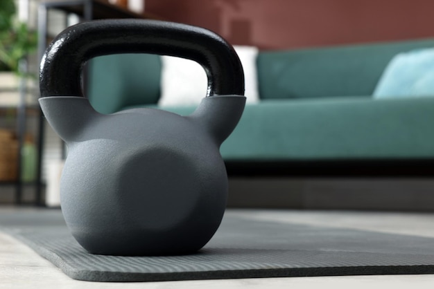 Kettlebell y colchoneta de yoga gris en el suelo de la habitación Espacio para texto