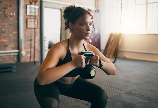 Foto kettlebell de fitness e uma mulher na academia fazendo exercícios de treino e treinamento de peso para o bem-estar do corpo e músculos esportes fortes feminino ou atleta com pesos para energia e um estilo de vida saudável