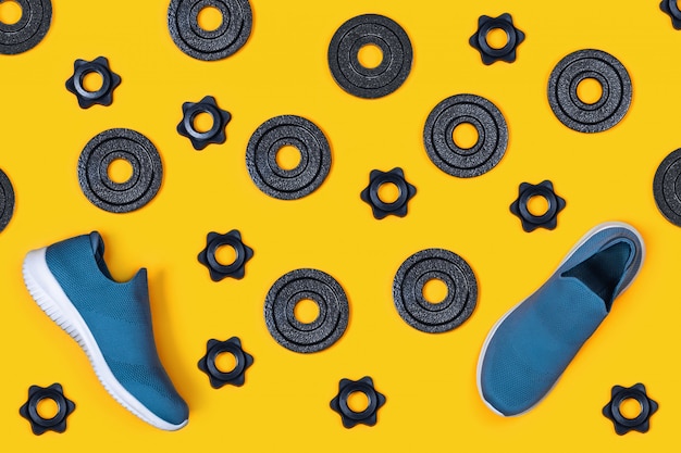 Kettlebells, pesas y zapatillas de deporte sobre fondo amarillo