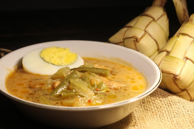 Ketupat es comida tradicional indonesia, hojas de coco tejidas rellenas de arroz y comido con papaya