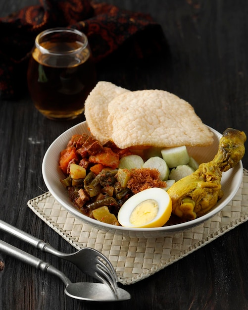 Ketupat Sayur o Lontong Sayur Lebaran Komplit Dish generalmente servido durante Ramadhan o Idul Fitri en mesa de madera servida con té