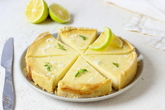 Key Lime Pie auf weißem Holz mit Limetten