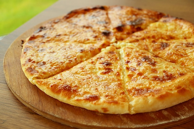 Khachapuri imeruli recém-assado imeretian ou pão achatado georgiano recheado com queijo em um prato de madeira