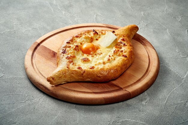 Khachapuri con queso derretido salado y yema de huevo en un plato Fondo de hormigón