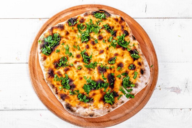 Foto khachapuri recién horneado con queso sobre un fondo de madera blanca