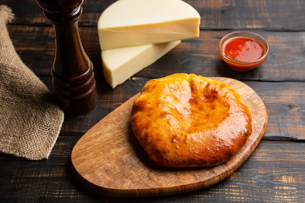 Khachapuri uzbeque com queijo com molho de tomate na tábua de cortar na mesa de madeira