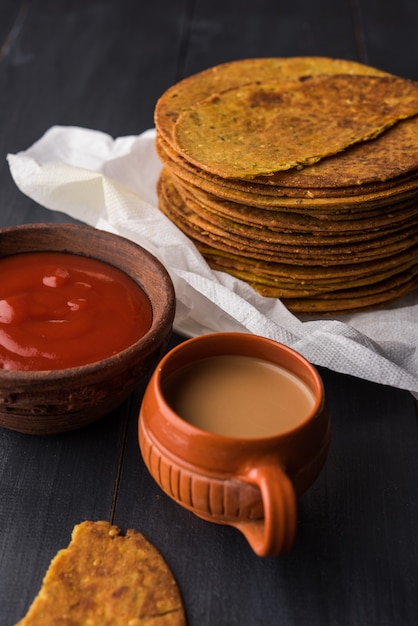 Khakhra o Khakra es una galleta fina que es un alimento popular para el desayuno Jain, Gujarati y Rajasthani. Servido con té caliente y salsa de tomate. Sobre fondo de colores o madera