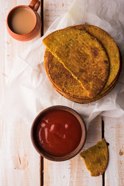 Khakhra o Khakra es una galleta fina que es un alimento popular para el desayuno Jain, Gujarati y Rajasthani. Servido con té caliente y salsa de tomate. Sobre fondo de colores o madera