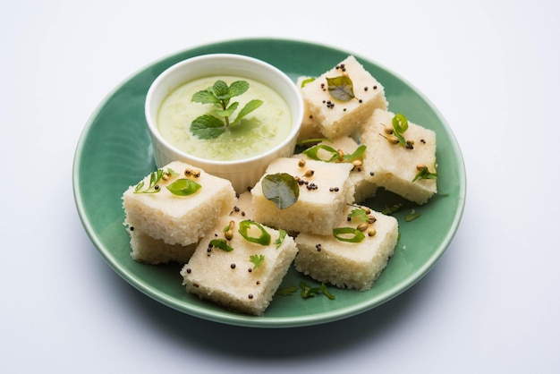 Khaman White Dhokla aus Reis oder Urad Dal ist ein beliebtes Frühstücks- oder Snackrezept aus Gujarat, Indien, serviert mit grünem Chutney und heißem Tee. Selektiver Fokus