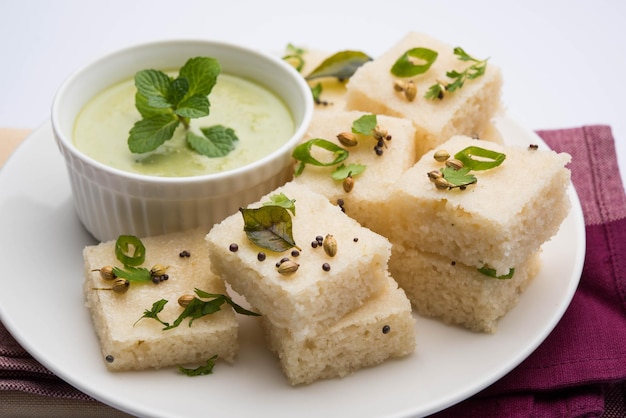 Khaman White Dhokla aus Reis oder Urad Dal ist ein beliebtes Frühstücks- oder Snackrezept aus Gujarat, Indien, serviert mit grünem Chutney und heißem Tee. Selektiver Fokus