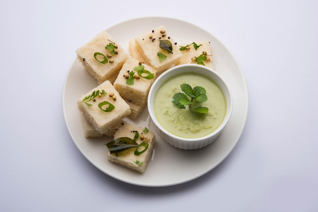 Khaman White Dhokla aus Reis oder Urad Dal ist ein beliebtes Frühstücks- oder Snackrezept aus Gujarat, Indien, serviert mit grünem Chutney und heißem Tee. Selektiver Fokus