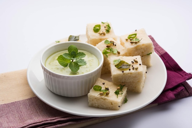 Khaman white dhokla feito de arroz ou urad dal é um café da manhã popular ou receita de lanches de gujarat, índia, servido com chutney verde e chá quente. foco seletivo