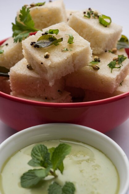 Khaman white dhokla feito de arroz ou urad dal é um café da manhã popular ou receita de lanches de gujarat, índia, servido com chutney verde e chá quente. foco seletivo