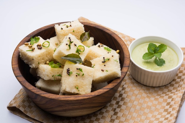 Khaman white Dhokla feito de arroz ou urad dal é um café da manhã popular ou receita de lanches de Gujarat, Índia, servido com chutney verde e chá quente. Foco seletivo